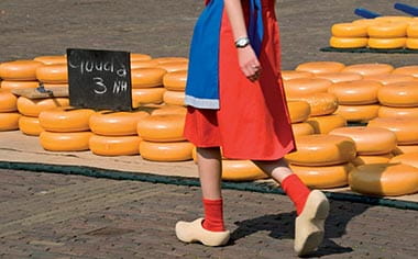 A woman wearing traditional wooden clogs, walking through the Alkmaar cheese market in the Netherlands